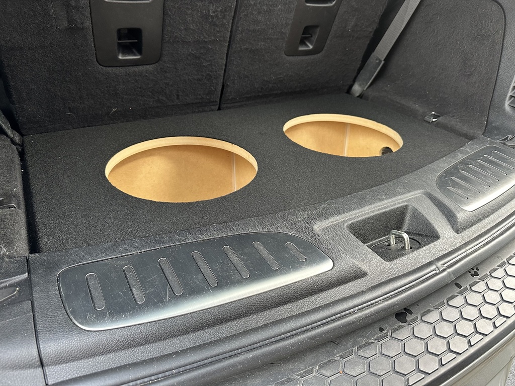empty subwoofer box fabricated into the floor of the trunk